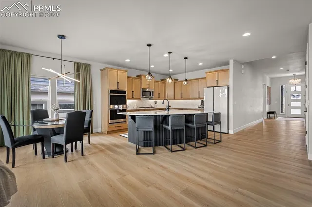 a large kitchen with stainless steel appliances refrigerator a dining table and chairs