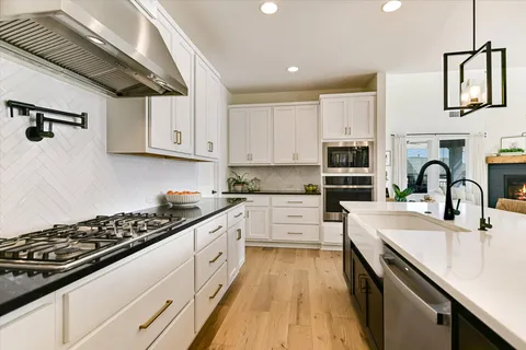 a kitchen with stainless steel appliances kitchen island granite countertop a kitchen island hardwood floor and a sink