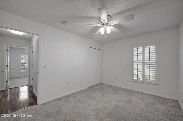 a view of empty room with wooden floor and ceiling fan