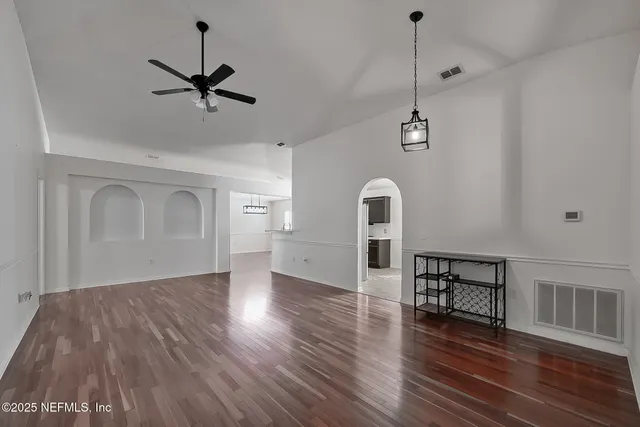 a view of empty room with wooden floor and fan