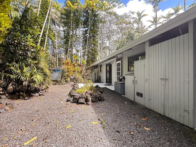 a backyard of a house with table and chairs and a large tree