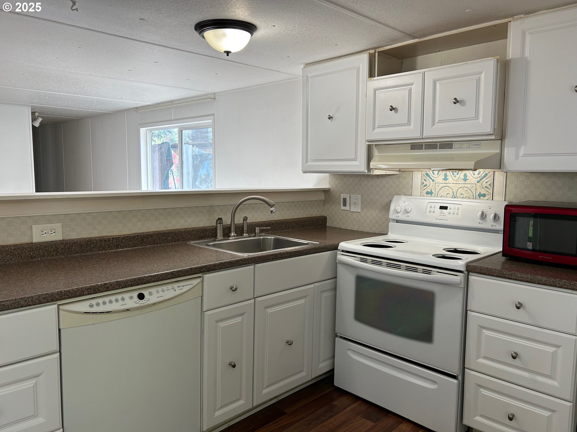 89510 Highway 101, Unit 26 Florence, OR 97439 - Photo 4 of 16 a kitchen with granite countertop white cabinets and white appliances