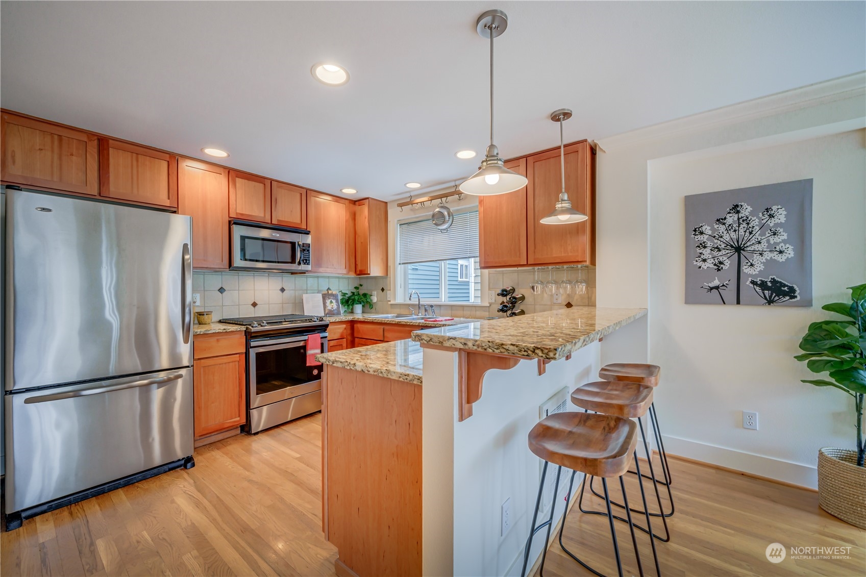 508 North 46th Street, Unit B Seattle, WA 98103 - Photo 11 of 30 a kitchen with stainless steel appliances granite countertop a refrigerator a stove a sink a dining table and chairs with wooden floor