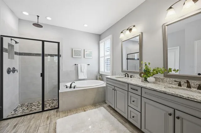 a bathroom with a granite countertop sink a mirror and a bathtub