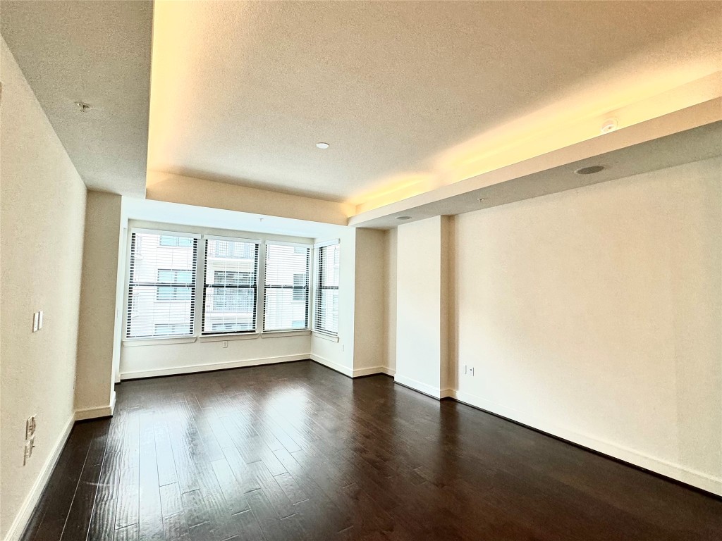 2303 Mid Lane, Unit 318 Houston, TX 77027 - Photo 3 of 25 an empty room with wooden floor and windows with curtains