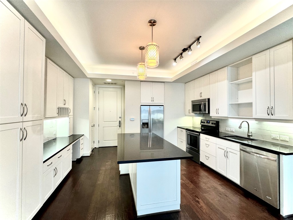 2303 Mid Lane, Unit 318 Houston, TX 77027 - Photo 7 of 25 a large kitchen with kitchen island a large counter space a sink appliances and cabinets