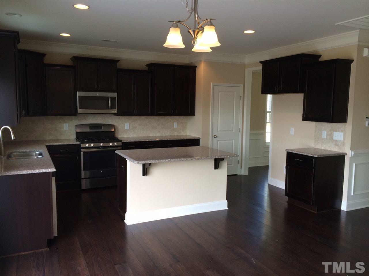 7464 Randshire Way Raleigh, NC 27616 - Photo 4 of 25 a kitchen with stainless steel appliances wooden cabinets and a wooden floor