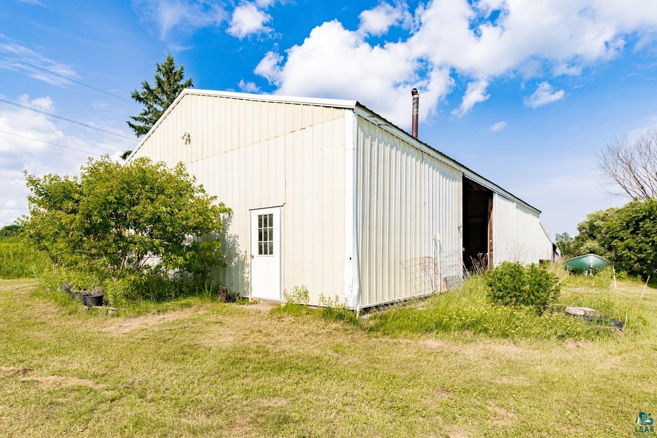 4800 Tower Road Moose Lake, MN 55767 - Photo 81 of 83 Metal-sided outbuilding featuring a white entry door with vertical lites, a chimney, and a large open bay