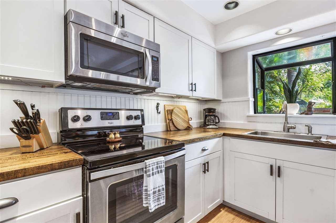 5432 Lower Honoapiilani Road, Unit B7 Lahaina, HI 96761 - Photo 8 of 27 a kitchen with stainless steel appliances granite countertop a sink a stove a microwave and wooden cabinets