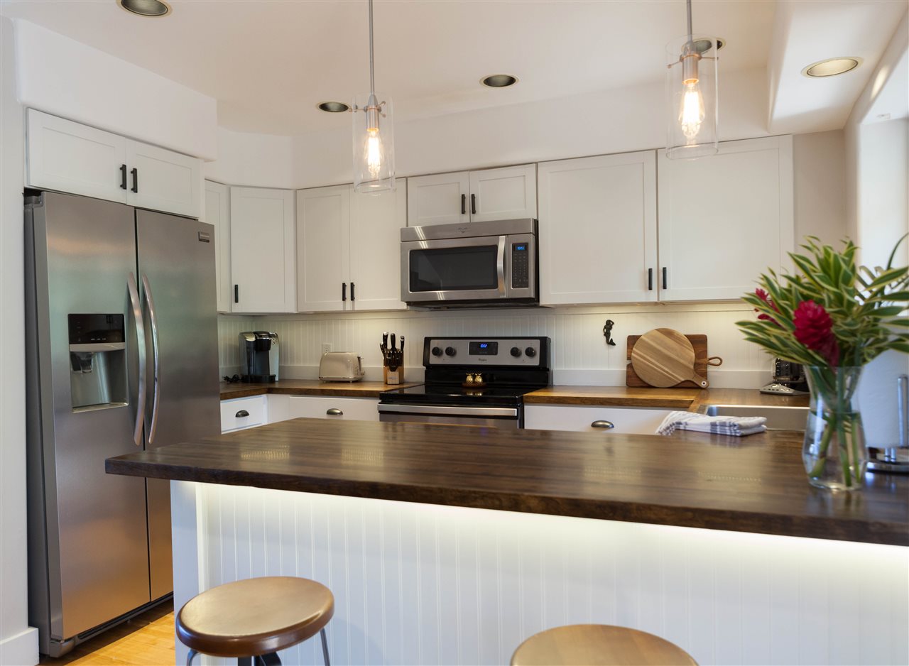 5432 Lower Honoapiilani Road, Unit B7 Lahaina, HI 96761 - Photo 9 of 27 a kitchen with granite countertop a refrigerator a stove a sink dishwasher and white cabinets with wooden floor