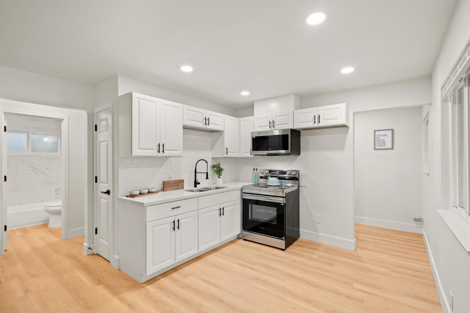 1719 West Swain Road, Unit A Stockton, CA 95207 - Photo 9 of 25 a kitchen with stainless steel appliances granite countertop a stove top oven a sink a refrigerator and white cabinets with wooden floor