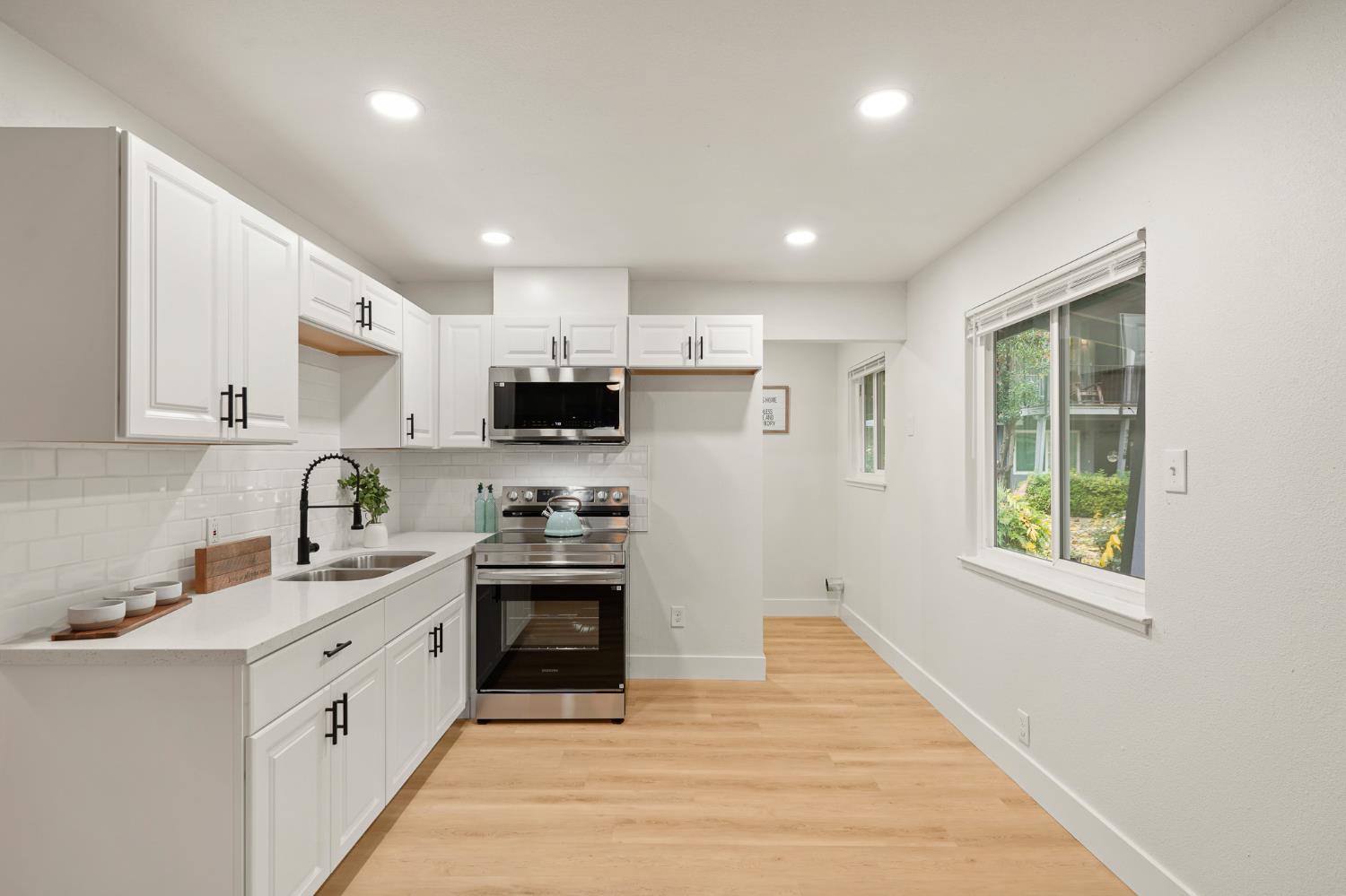 1719 West Swain Road, Unit A Stockton, CA 95207 - Photo 10 of 25 a large kitchen with stainless steel appliances granite countertop a stove a sink dishwasher and a refrigerator with wooden floor