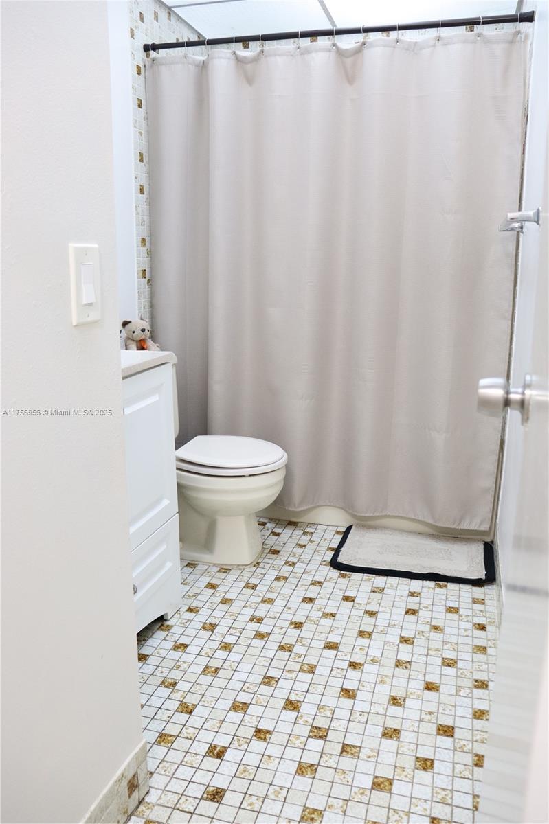 8025 Southwest 107th Avenue, Unit 222 Miami, FL 33173 - Photo 9 of 27 a bathroom with a toilet and a shower curtain