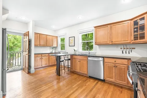 a open kitchen with granite countertop a stove top oven a sink dishwasher a dining table and chair with wooden floor