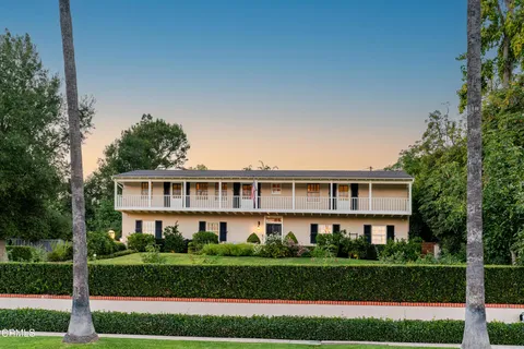 a front view of a house with a yard and potted plants