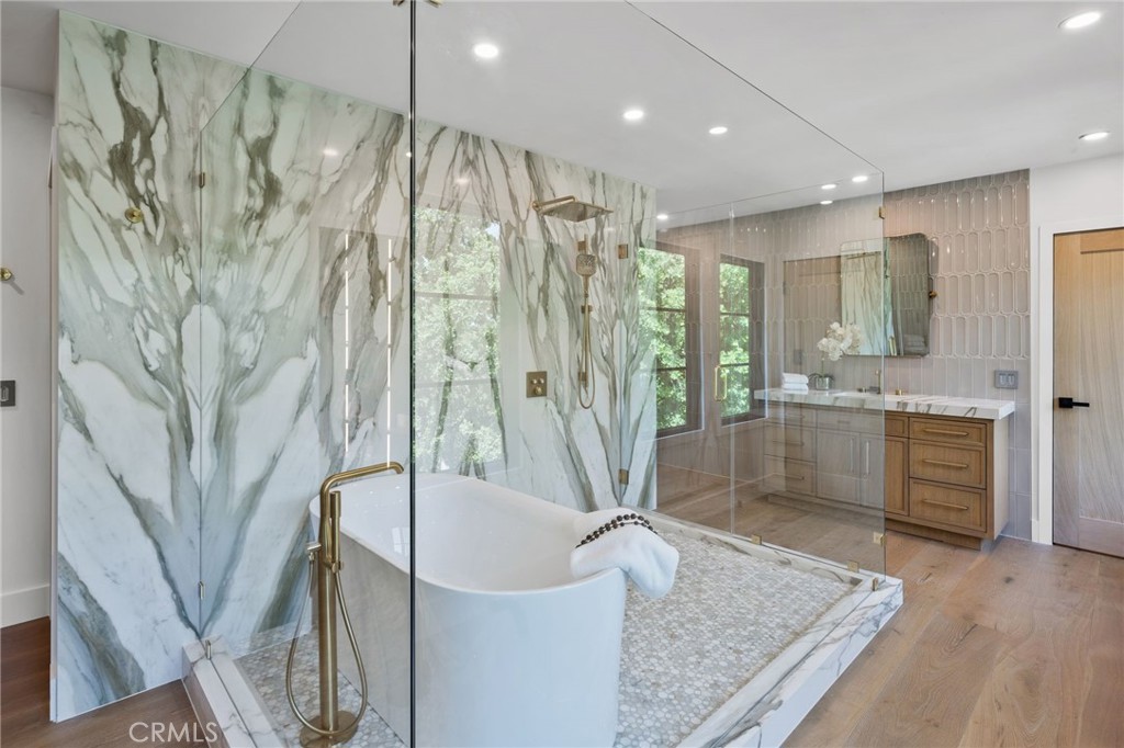 5510 Hoback Glen Road Hidden Hills, CA 91302 - Photo 35 of 60 a bathroom with a granite countertop sink a mirror a bathtub and shower