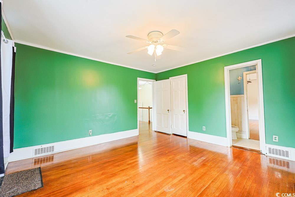 509 Beaty Street Conway, SC 29526 - Photo 23 of 40 Unfurnished bedroom with hardwood / wood-style flooring, a ceiling fan, connected bathroom, and crown molding