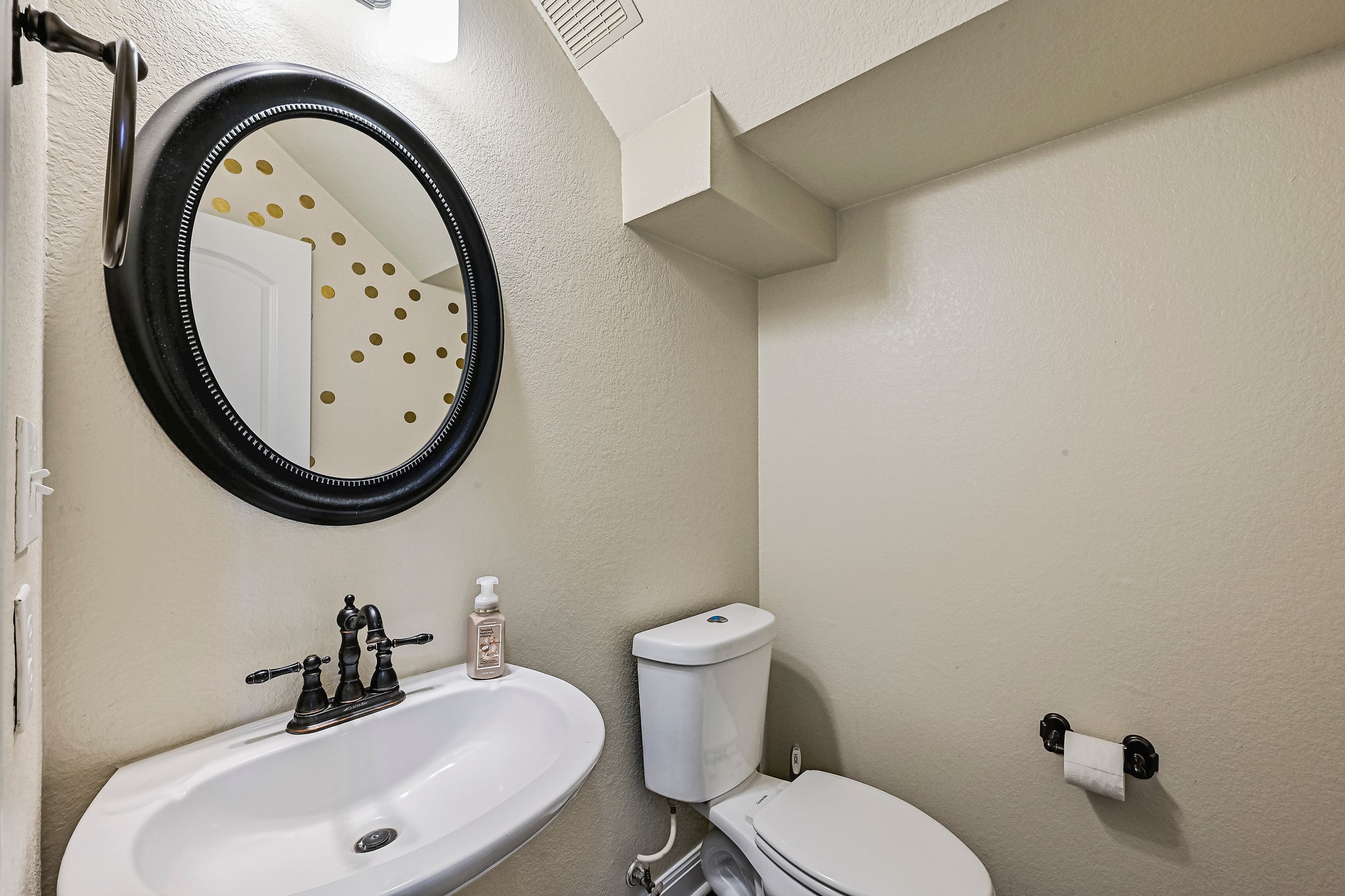 2408 Amen Corner Road Pflugerville, TX 78660 - Photo 22 of 40 Pedestal sink with dark bronze fixtures, complemented by an oval framed mirror
