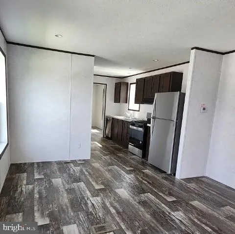a view of kitchen with refrigerator cabinets and wooden floor
