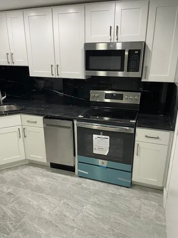 a kitchen with granite countertop white cabinets and stainless steel appliances