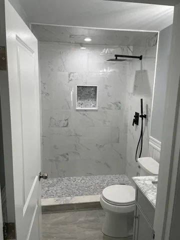 a bathroom with a granite countertop toilet a sink and shower