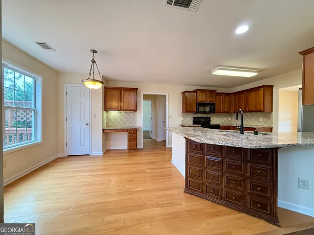 a large kitchen with stainless steel appliances granite countertop a sink and cabinets