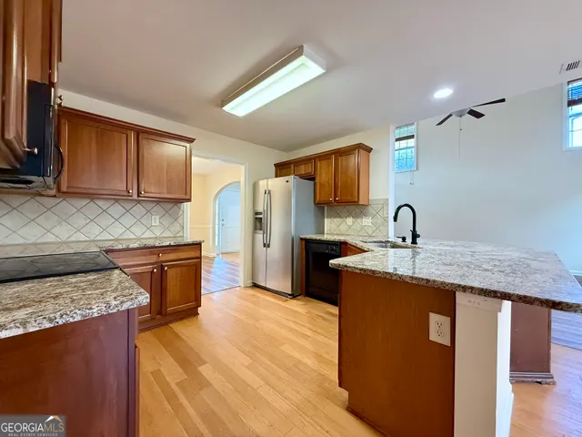 a large kitchen with stainless steel appliances granite countertop a stove and a wooden floors