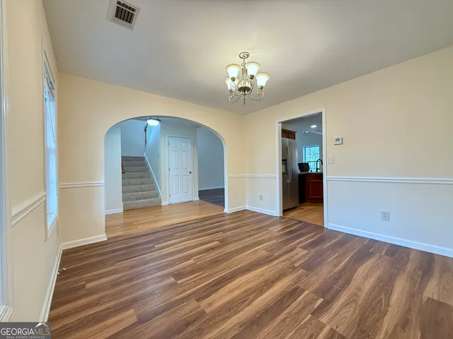 an empty room with wooden floor chandelier and entryway