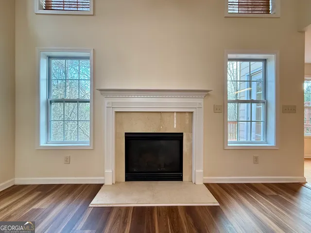 an empty room with wooden floor fireplace and windows