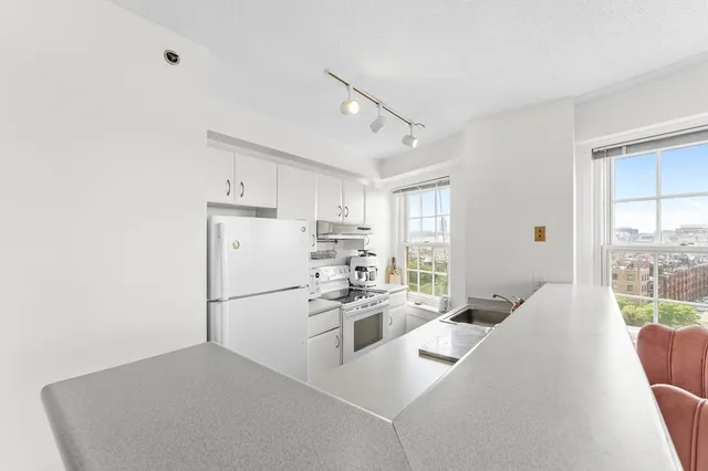 a kitchen with stainless steel appliances a refrigerator a stove a sink dishwasher and white cabinets with wooden floor