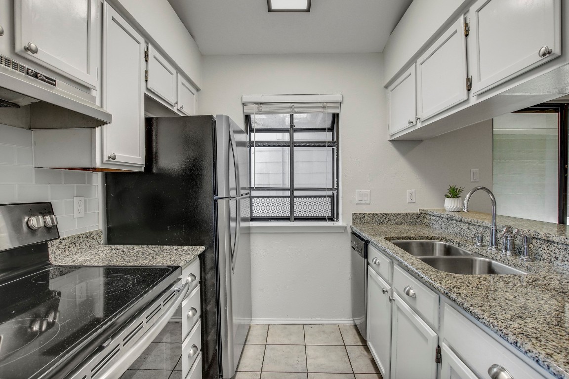 2215 Post Road, Unit 2022 Austin, TX 78704 - Photo 6 of 15 Kitchen featuring stainless steel appliances, light stone countertops, under cabinet range hood, backsplash, and light tile patterned floors