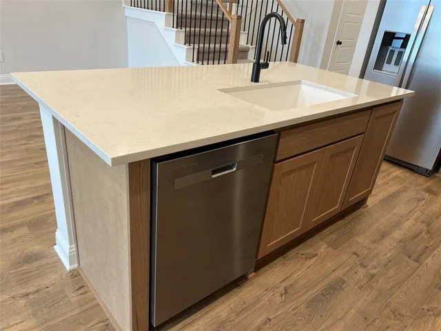 a kitchen with a sink a refrigerator and wooden floor