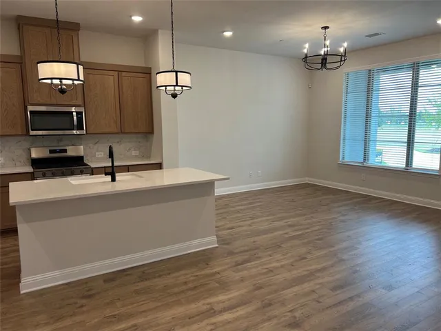 a view of a hallway with wooden floor and a bathroom