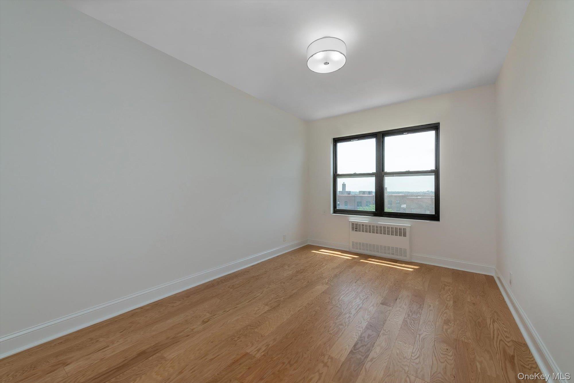 99-52 66th Road, Unit W7 Queens, NY 11374 - Photo 14 of 22 an empty room with wooden floor and windows