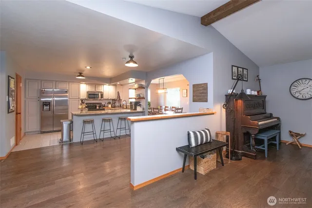 a living room with couches and kitchen view with wooden floor