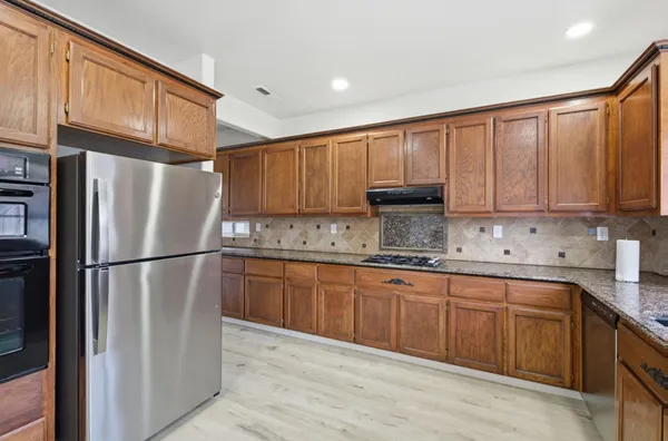 a kitchen with stainless steel appliances granite countertop wooden cabinets a sink and dishwasher a refrigerator with wooden cabinets