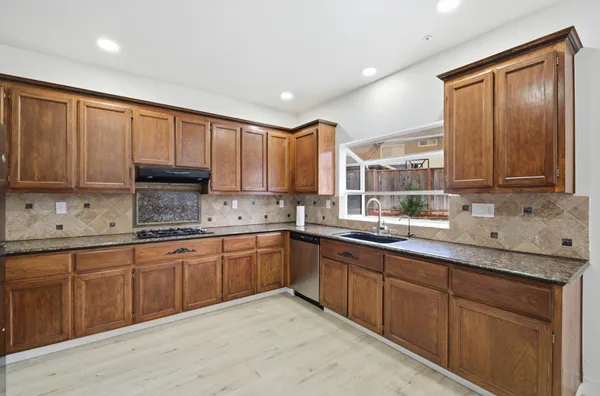 a kitchen with stainless steel appliances granite countertop a sink a stove and cabinets