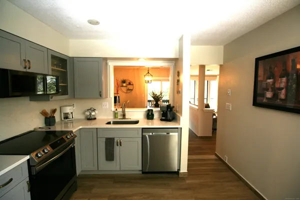 a kitchen with stainless steel appliances a sink a stove cabinets and wooden floor