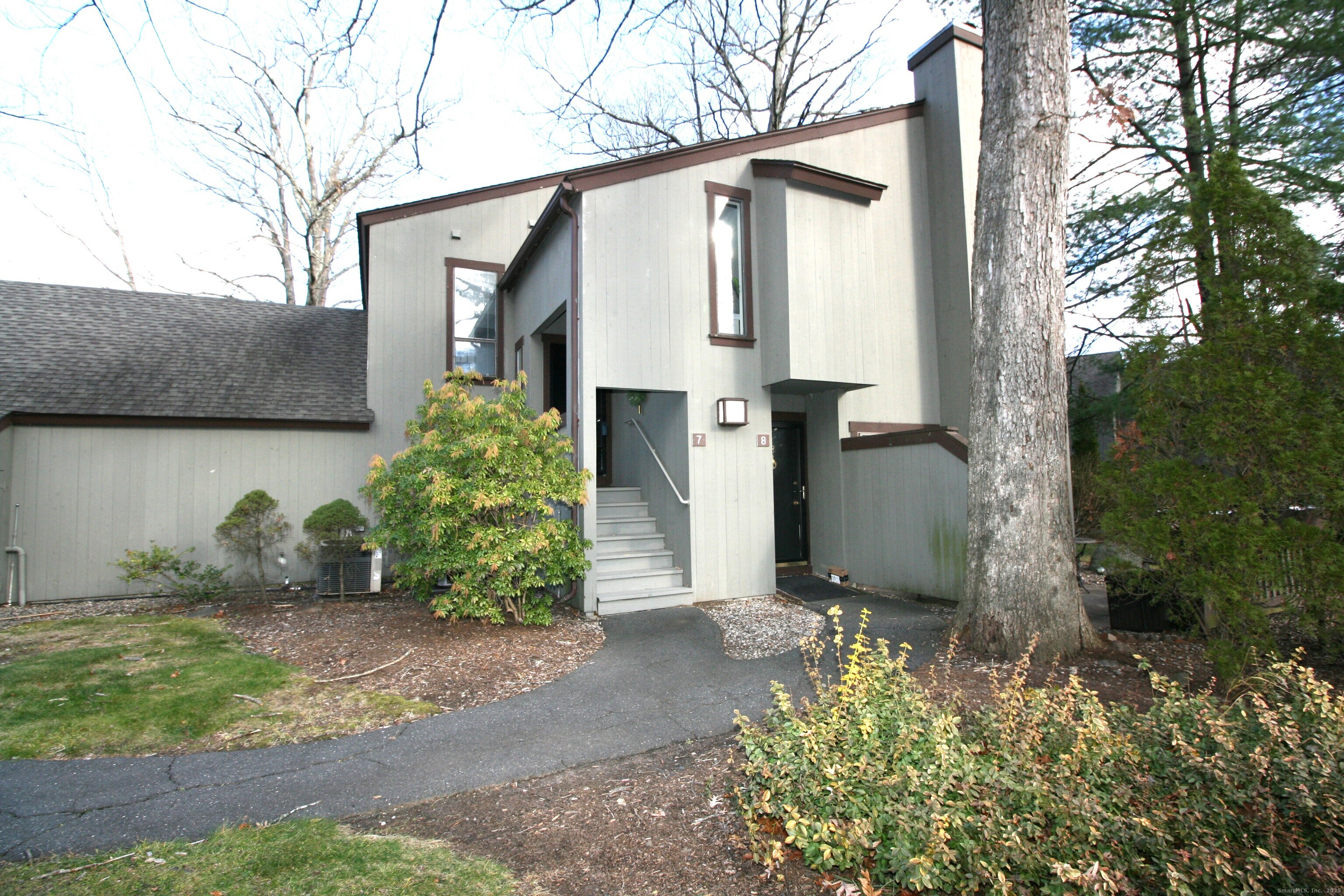 7 Twin Oak Court, Unit 7 Avon, CT 06001 - Photo 2 of 32 a view of a small house with potted plants and a large tree
