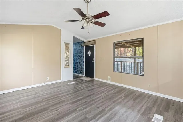 a view of an empty room with wooden floor and a window