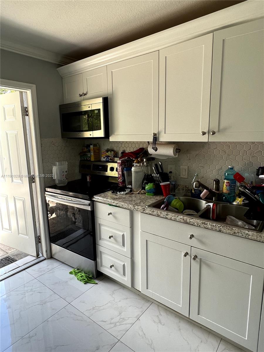 554 West 2nd Street Riviera Beach, FL 33404 - Photo 5 of 11 a kitchen with stainless steel appliances granite countertop white cabinets sink and a granite counter top