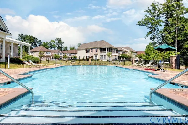 a view of swimming pool with lawn chairs and large trees