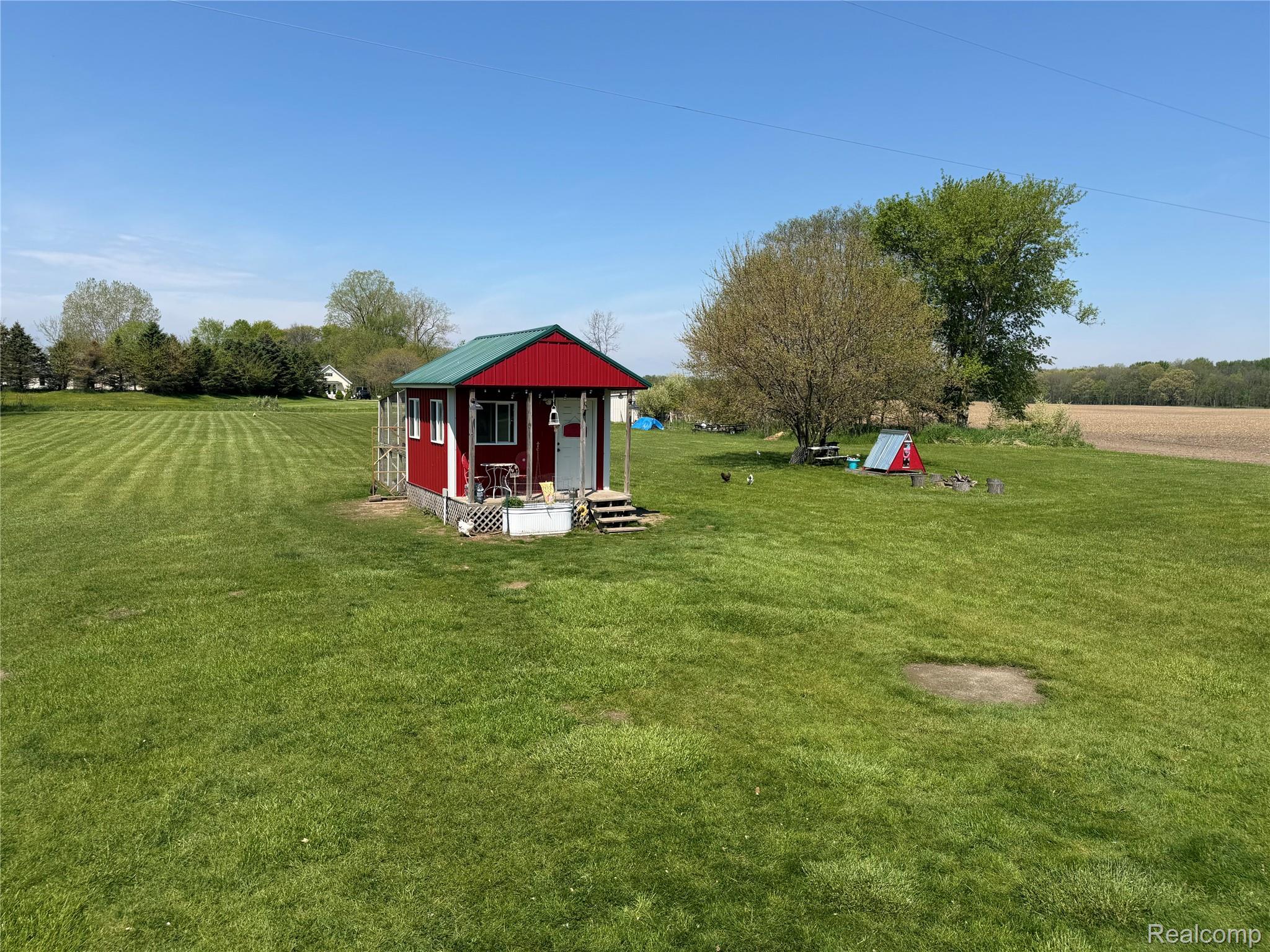6860 Grand River Road Bancroft, MI 48414 - Photo 25 of 31 View of green lawn featuring an outbuilding, a view of countryside, and covered porch
