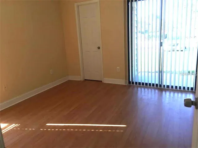 an empty room with wooden floor and windows with curtains
