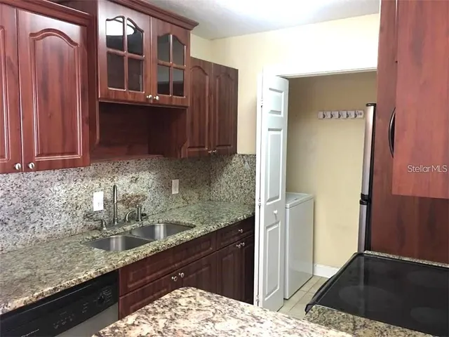 a kitchen with granite countertop a refrigerator and a sink