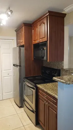 a kitchen with granite countertop a refrigerator stove and microwave