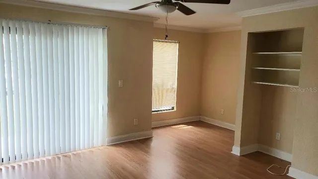 an empty room with wooden floor closet and windows