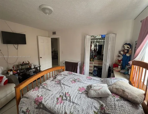 a bedroom with a bed and a flat tv screen on the dresser
