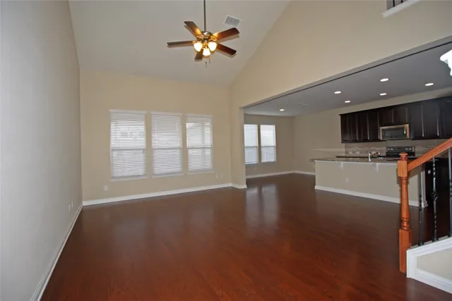 a view of an empty room with kitchen and window