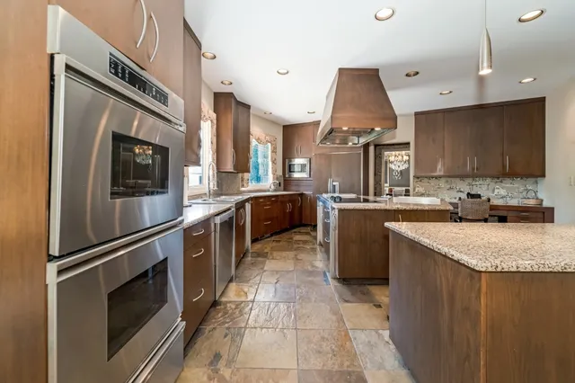 a kitchen with stainless steel appliances granite countertop a refrigerator a stove and a sink